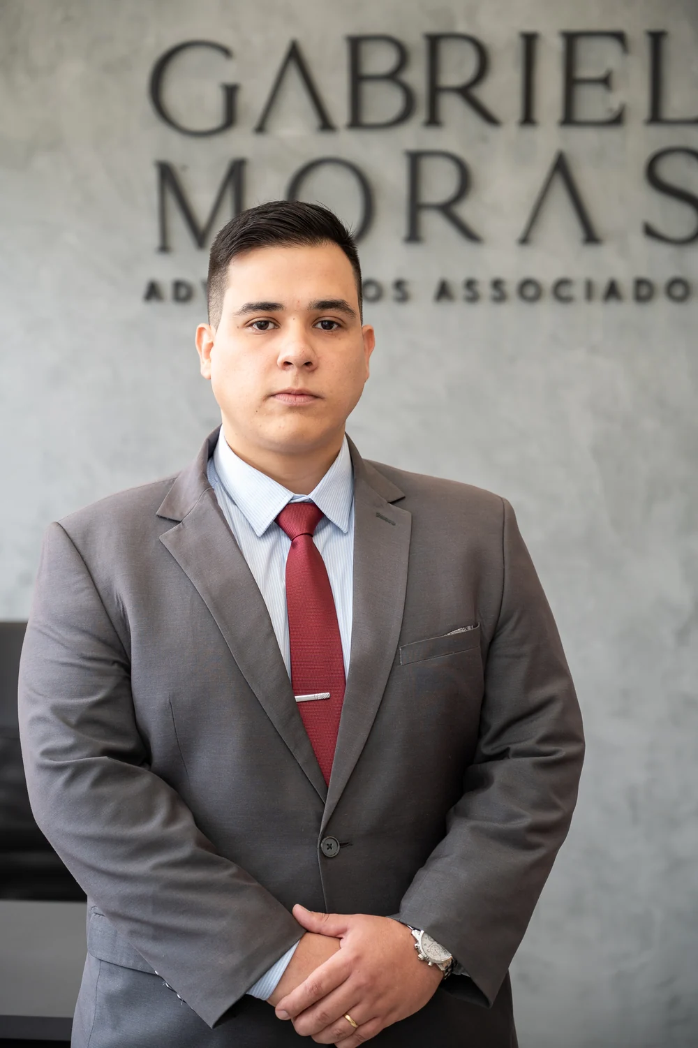 Gabriel Moras no escritório em Barbacena, diante da identidade visual da advocacia
